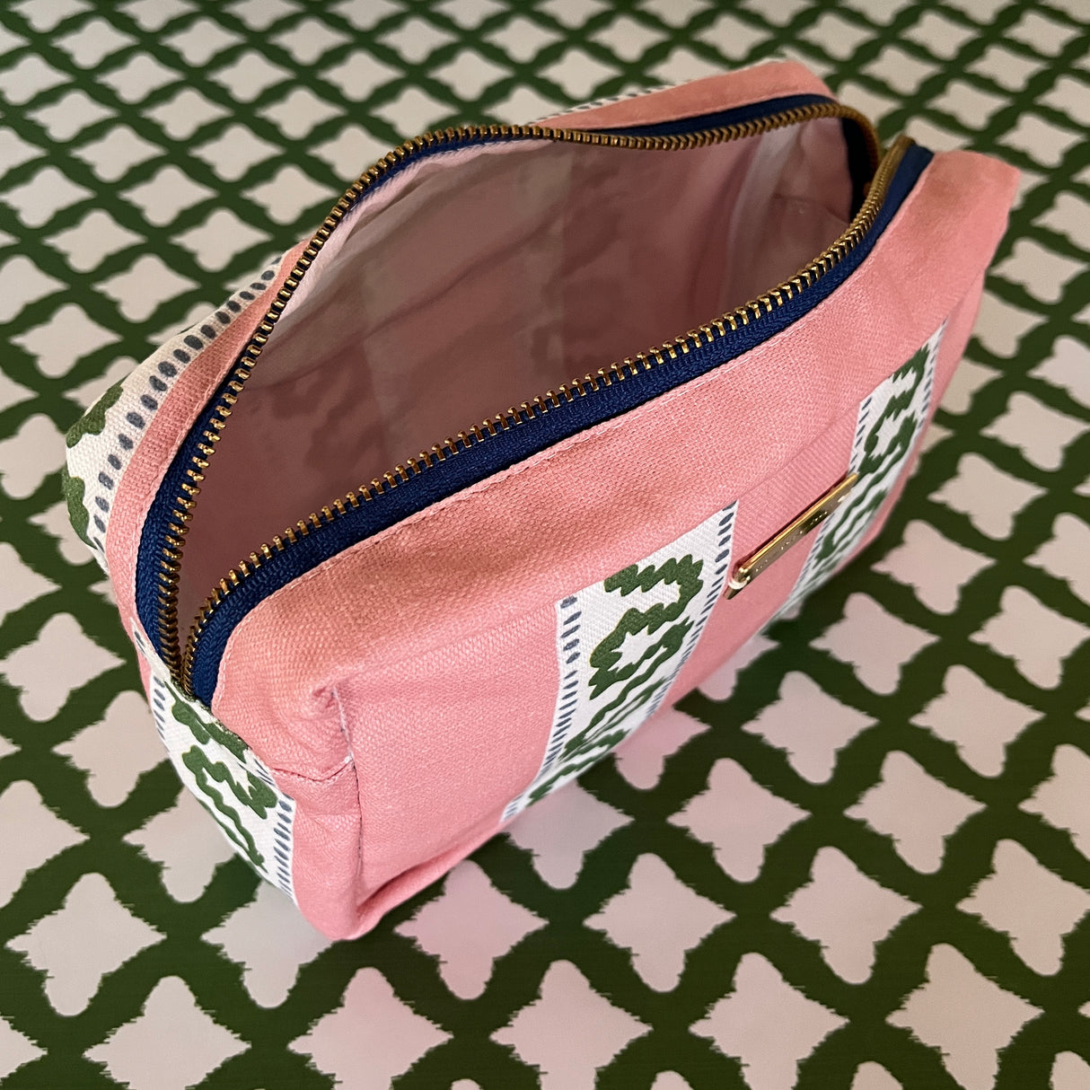 Interior view of Harbor Trail toiletry bag in Bahama pink with a green ribbon and blue dash motif.