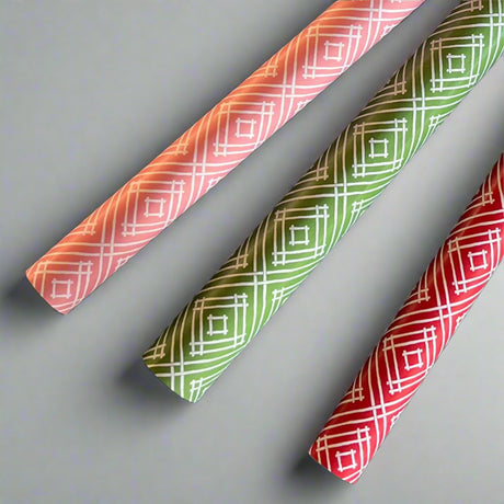 three Rolls of wrapping paper with a geometric lattice pattern in red, pink and green