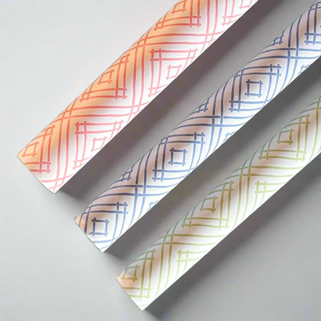 Rolls of gift wrapping paper with a geometric lattice pattern in green, blue, and pink colors.