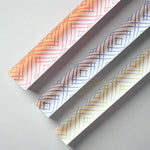 Rolls of gift wrapping paper with a geometric lattice pattern in green, blue, and pink colors.