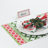 table setup featuring Island House Bamboo Trellis red place card with white plate, red floral napkin, and rattan bow napkin ring on green and red patterned placemat.