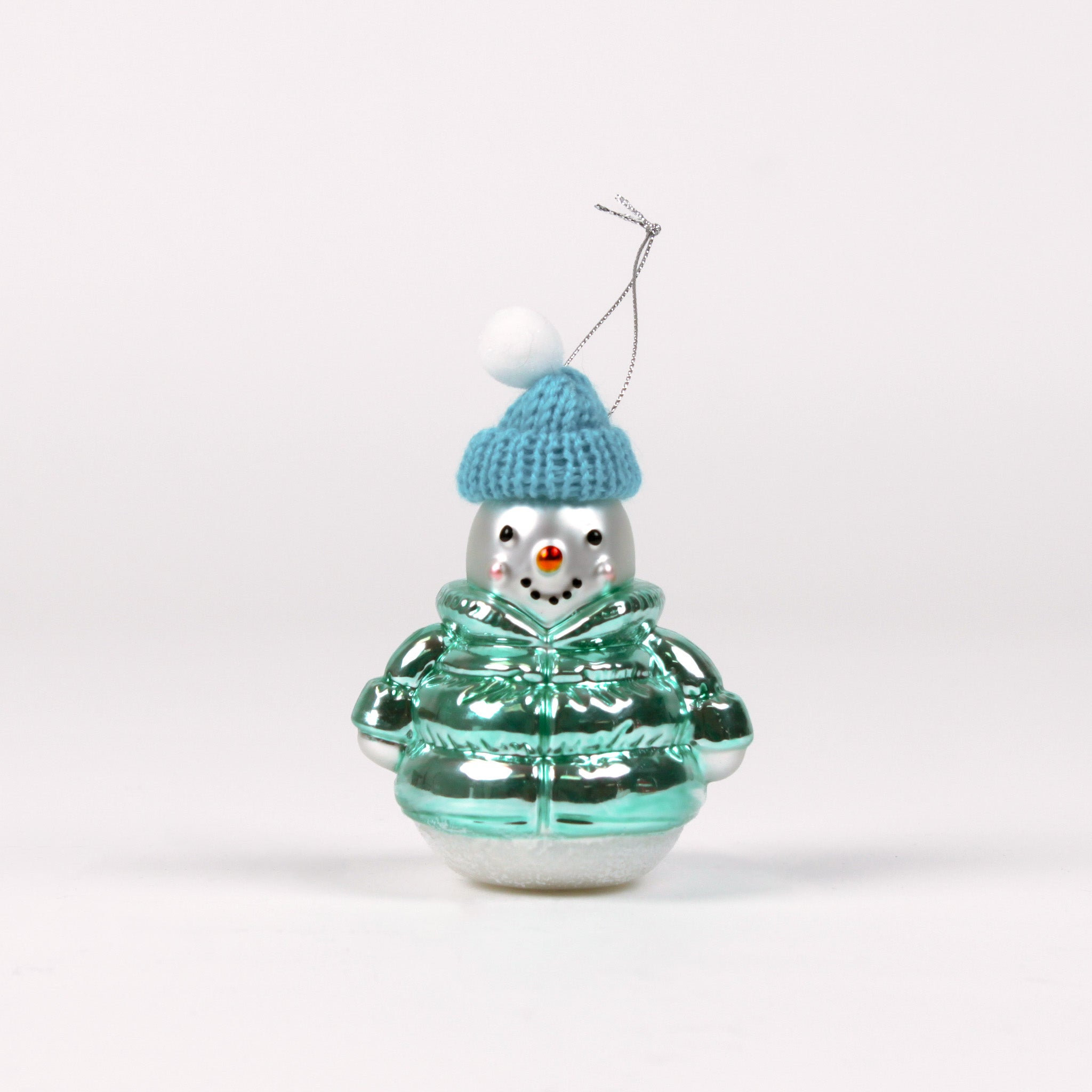 Glass snowman ornament with a blue hat and green jacket on a white background
