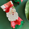 Hand-painted metal napkin rings featuring a Jolly Santa design, set on a green textured background.
