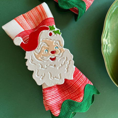 Hand-painted metal napkin rings featuring a Jolly Santa design, set on a green textured background.