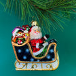 A glittery Sleigh with Santa Christmas Ornament against a green background