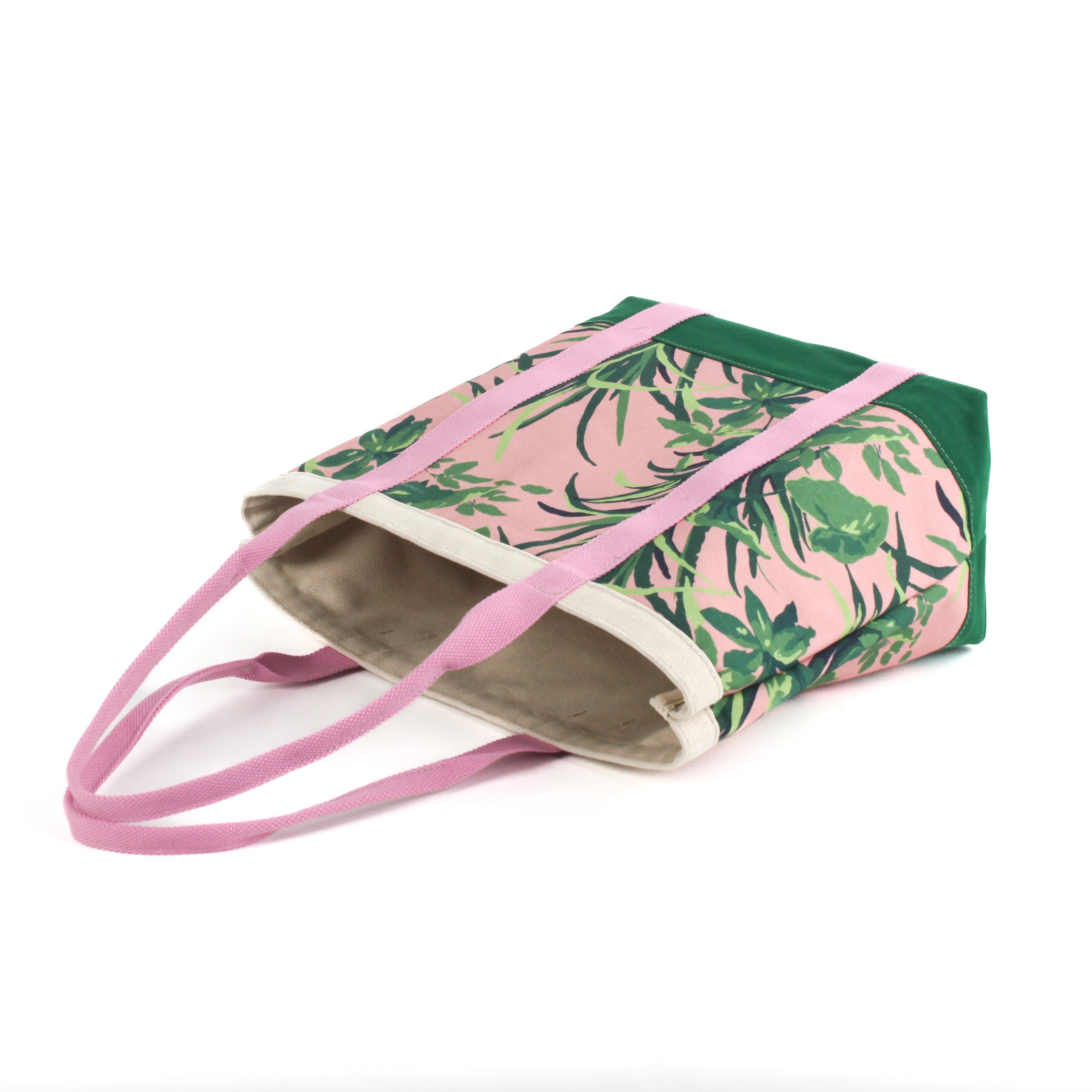 a large Jungle Road canvas tote bags with a pink and green leaf pattern, displayed lying in a white surface.