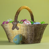 Large brown ceramic basket with woven texture and handle, styled with decorative eggs and green filler