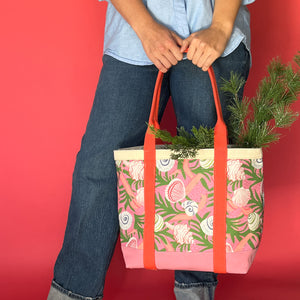 Shell Seekers large canvas tote bag with pink fabric with a repeating seaweed and shell motif held by model in front of their legs