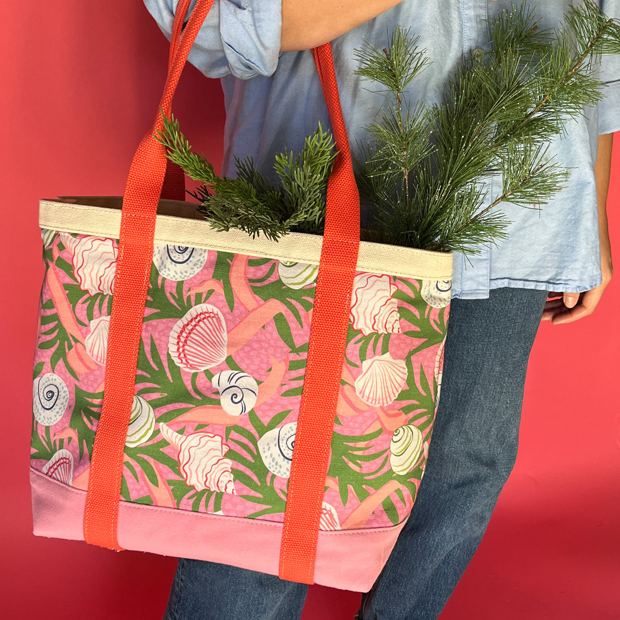 Shell Seekers canvas tote bag with pink fabric with a repeating seaweed and shell motif with greenery sticking out.