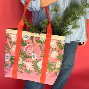 Shell Seekers canvas tote bag with pink fabric with a repeating seaweed and shell motif with greenery sticking out.