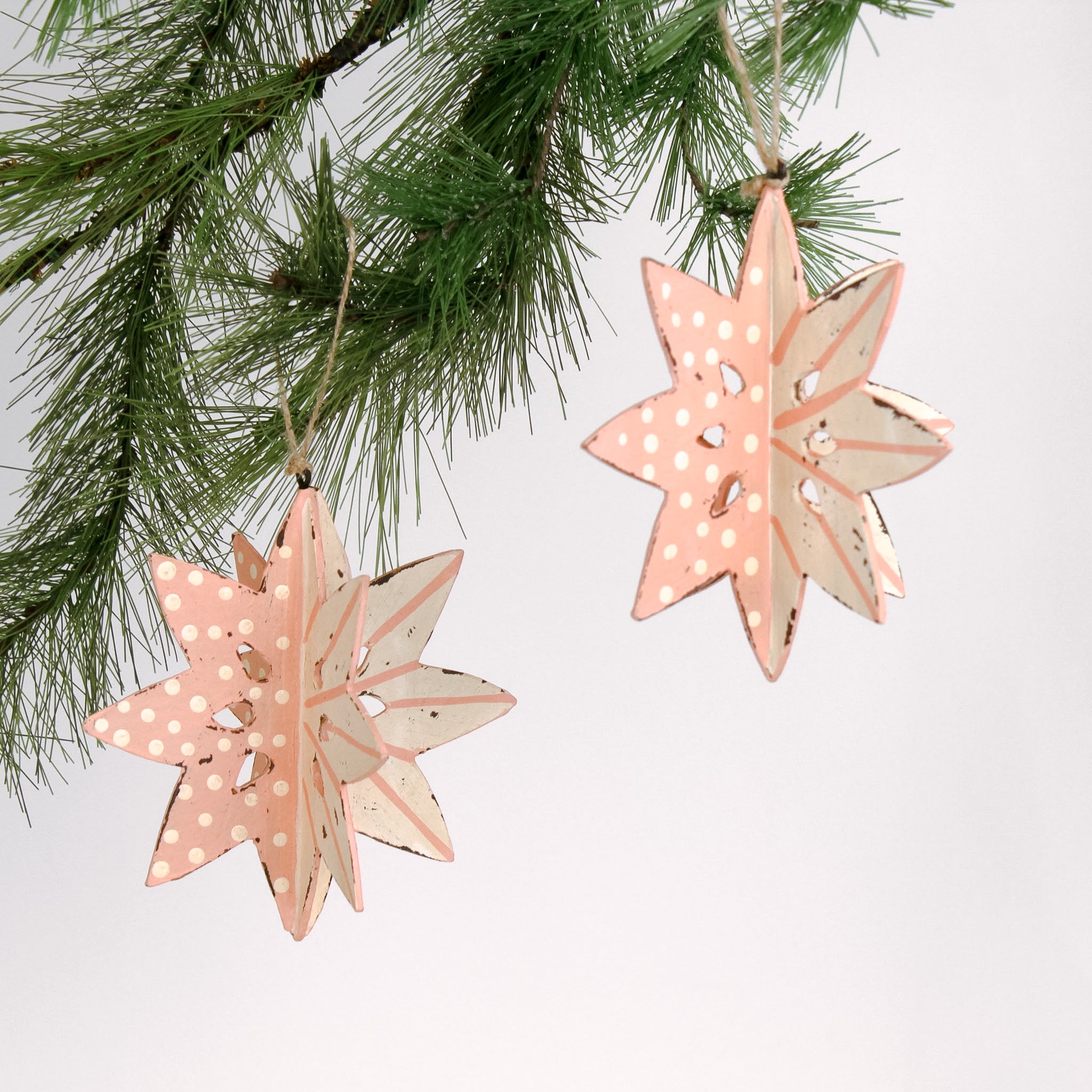 Set of two large wooden star christmas ornaments painted in pink and white with distressed polka dot details