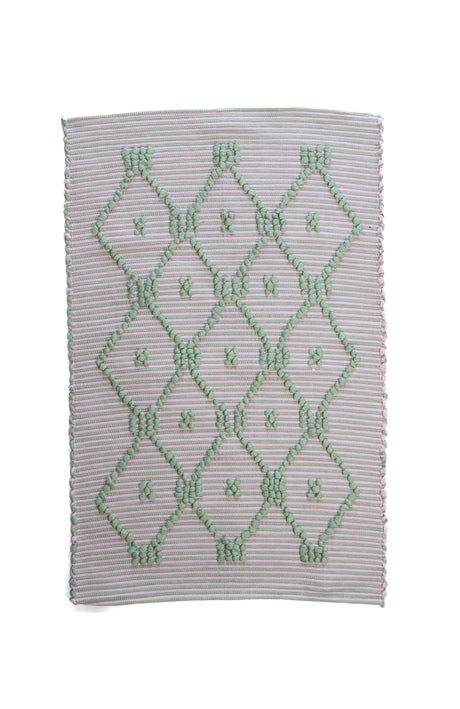 A madcap cottage pink and green striped accent rug with a lattice motif across the front