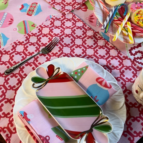 Lifestyle shot of Monserrat cloth placemat in red and light pink on a table with candy dishes and holiday napkins