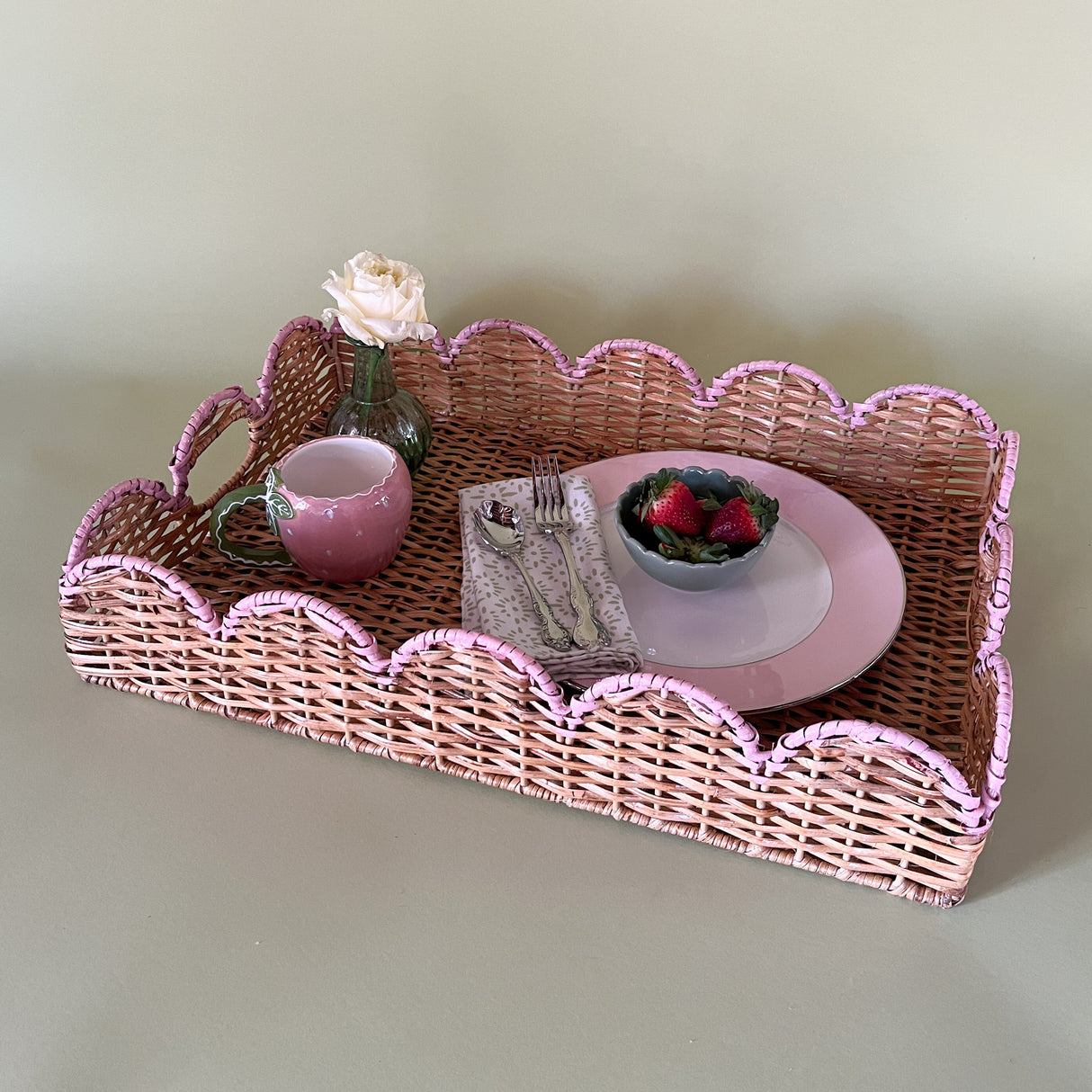 Lifestyle Scalloped Hand Painted Pink Rattan Tray with a place setting and fresh berries and flowers