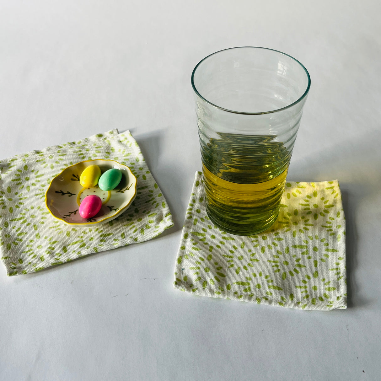 Lifestyle shot of Toujours Provence cloth cocktail napkins with a glass and trinket dish