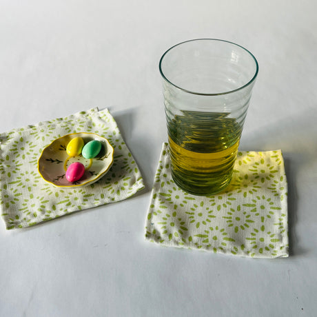 Lifestyle shot of Toujours Provence cloth cocktail napkins with a glass and trinket dish