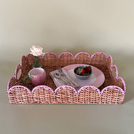 syled rattan tray with a pink scalloped edge holding a plate, mug, bud vase