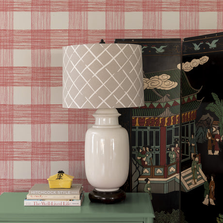 A beige lamp against a wall of large scale pink gingham wallpaper 