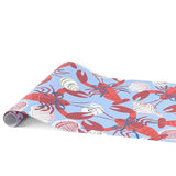 A blue coastal paper table runner with lobster and shell pattern on a white background
