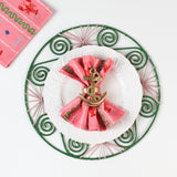 Pink lobster print fabric dinner napkin folded with a gold anchor napkin ring on a white plate and green placemat