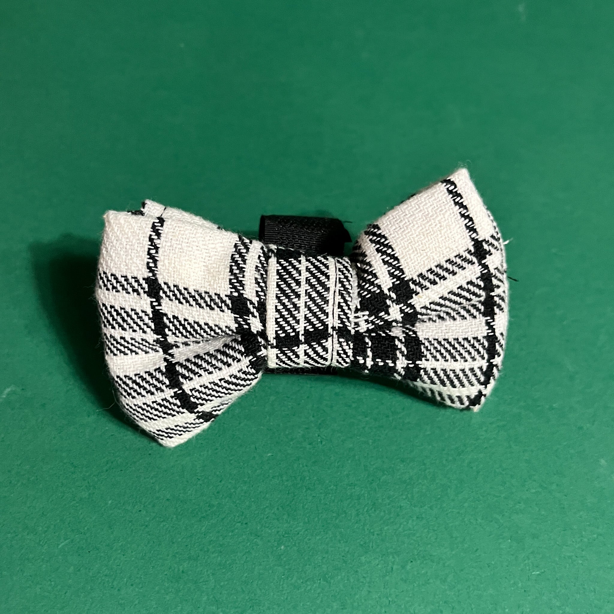 a MacLoecke Black/White Plaid Dog/Cat Bowties placed on a green surface