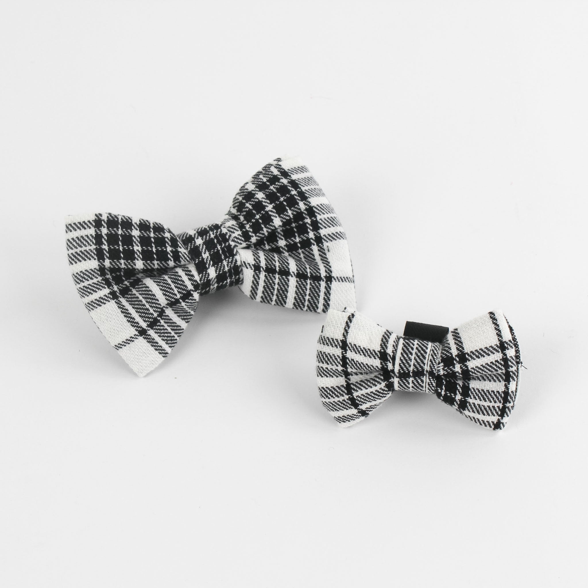 2 MacLoecke Black/White Plaid Dog/Cat Bowties in Medium and Large placed on a white surface