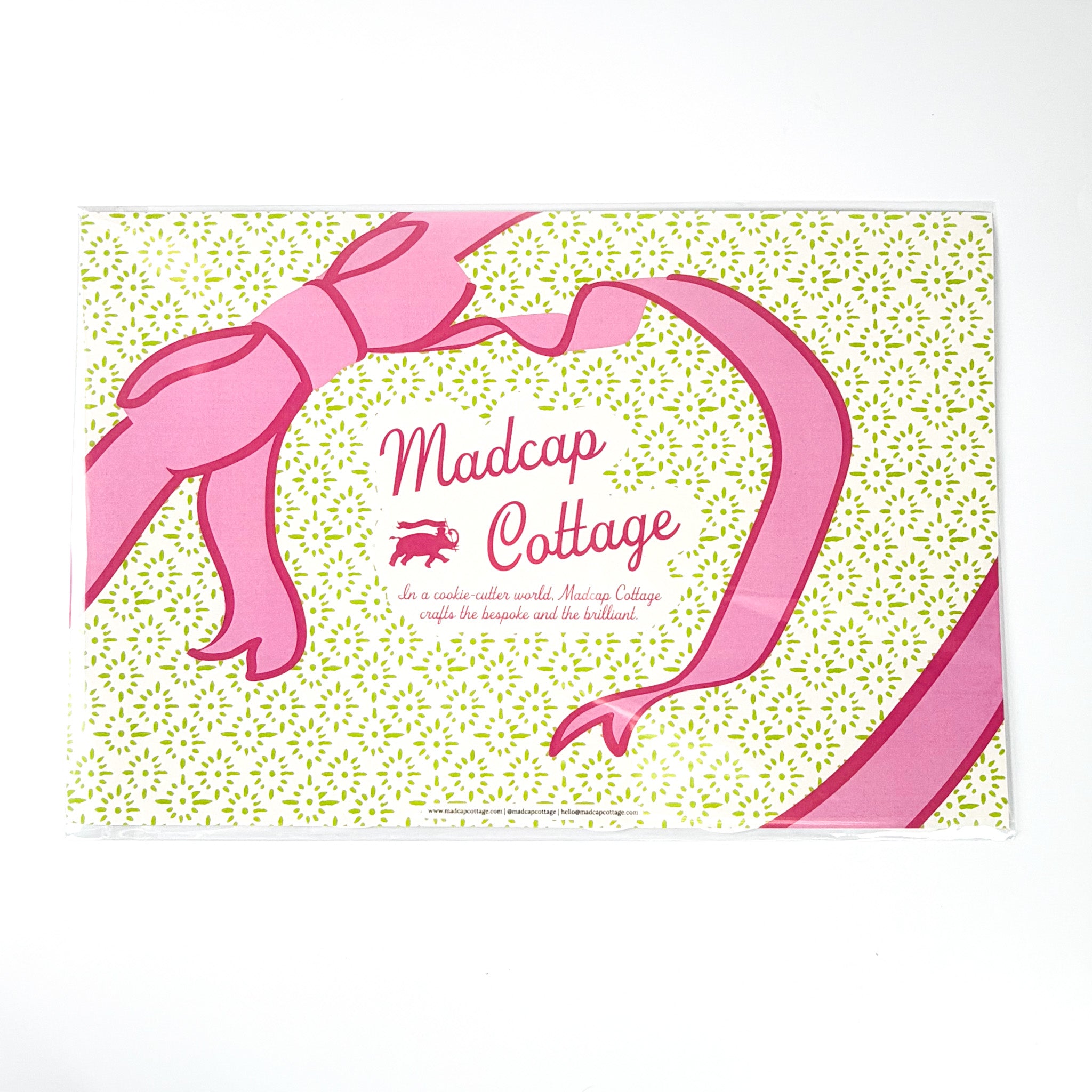 Madcap Cottage branded gift wrap featuring pink ribbon bow illustration and green patterned background with logo text, displayed on a white background.