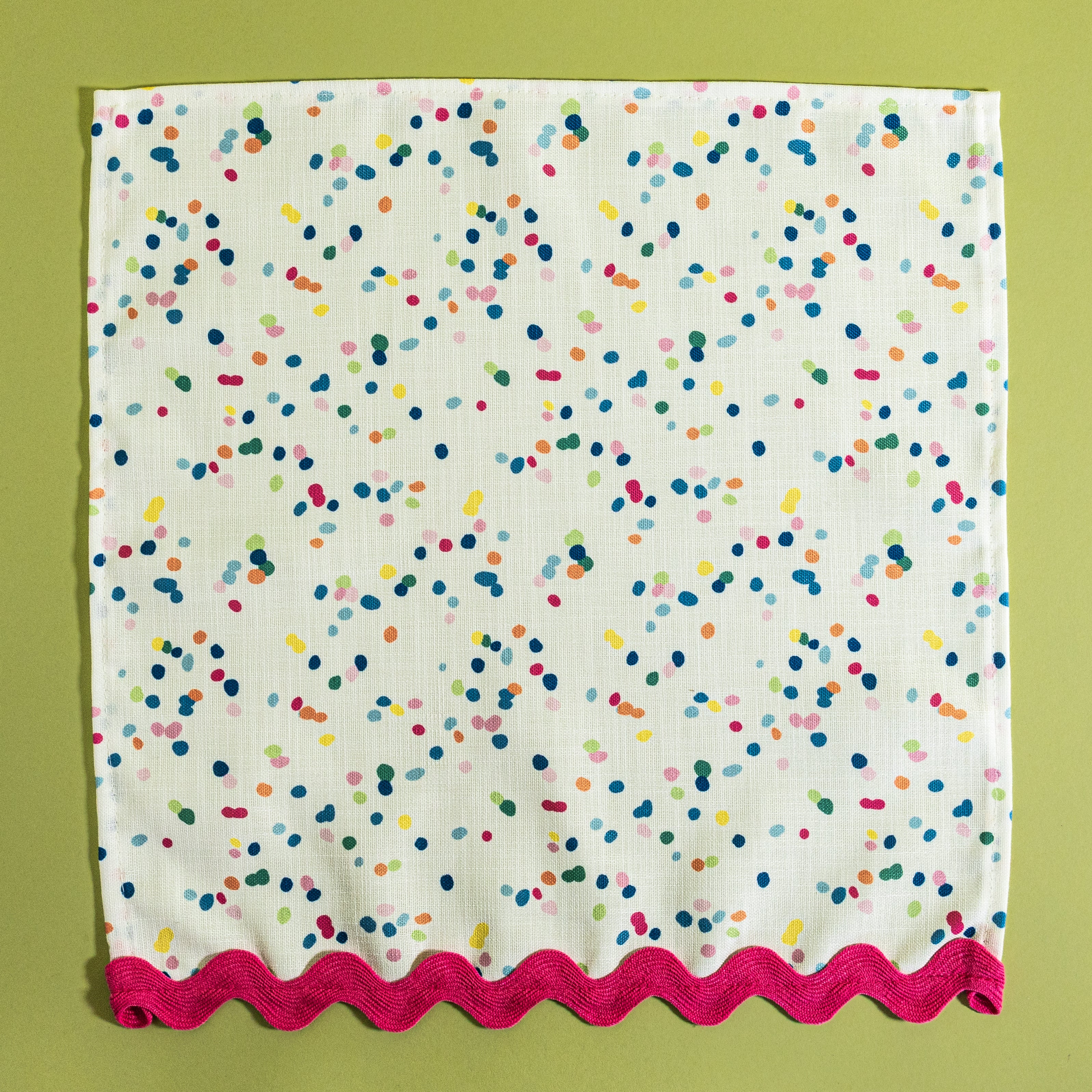 An open view of Springtime confetti multicolor cloth dinner napkin from Madcap Cottage on a light green background.