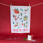 A christmas tea towel with festive motifs and text that reads North Pole