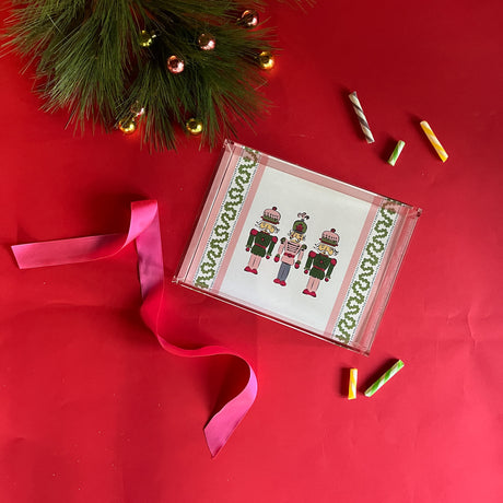Three Nutcrackers on white background bordered with pink, blue, and green acrylic trays in 3 sizes.
