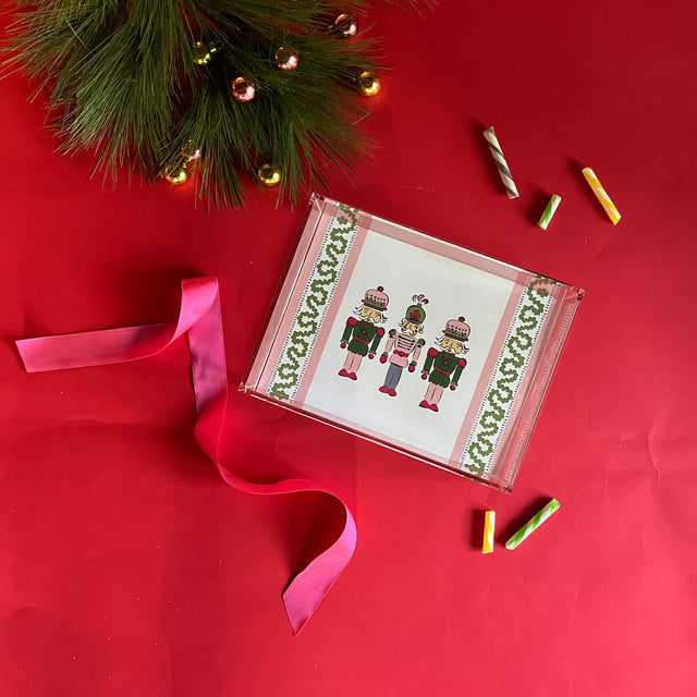 Three Nutcrackers on white background bordered with pink, blue, and green acrylic trays in 3 sizes.