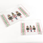 Three Nutcrackers on white background bordered with pink, blue, and green acrylic trays in 2 sizes.