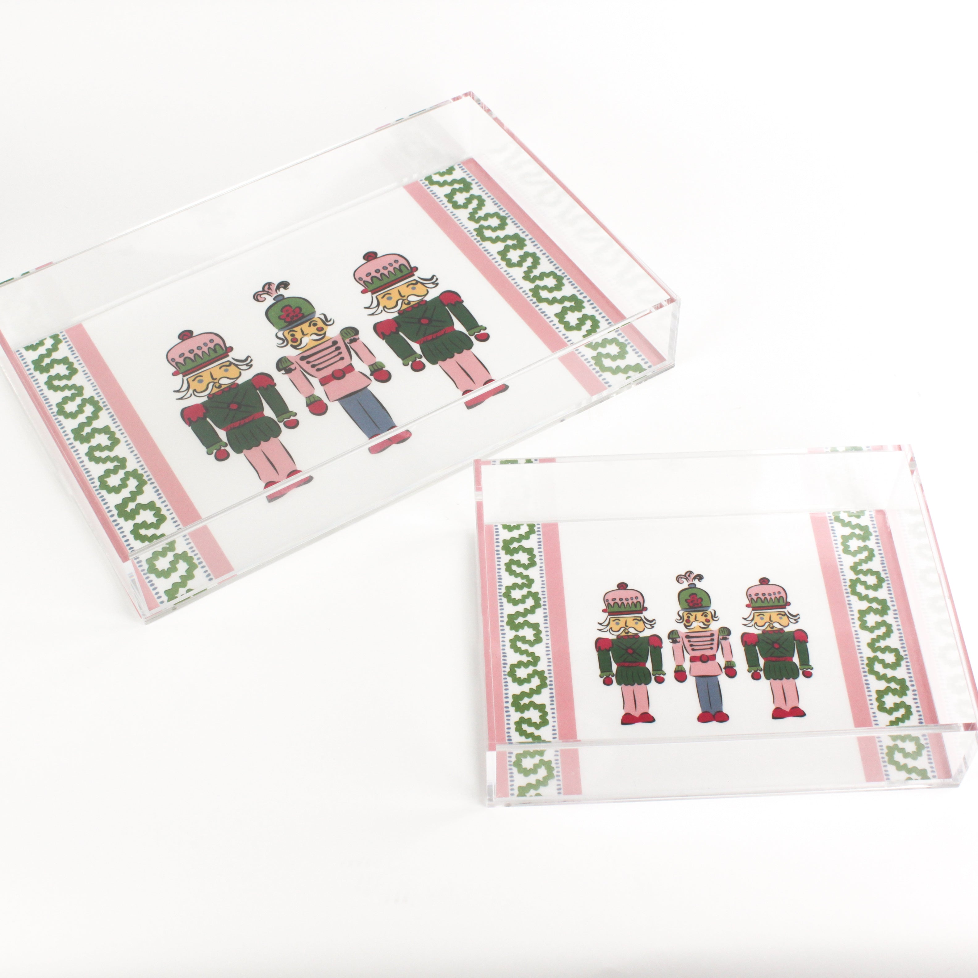 Three Nutcrackers on white background bordered with pink, blue, and green acrylic trays in 2 sizes.