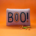 Madcap Cottage Pink halloween throw pillow with black and orange text that says Boo on an orange background with halloween candy in foreground.
