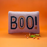 Madcap Cottage Pink halloween throw pillow with black and orange text that says Boo on an orange background with halloween candy in foreground.