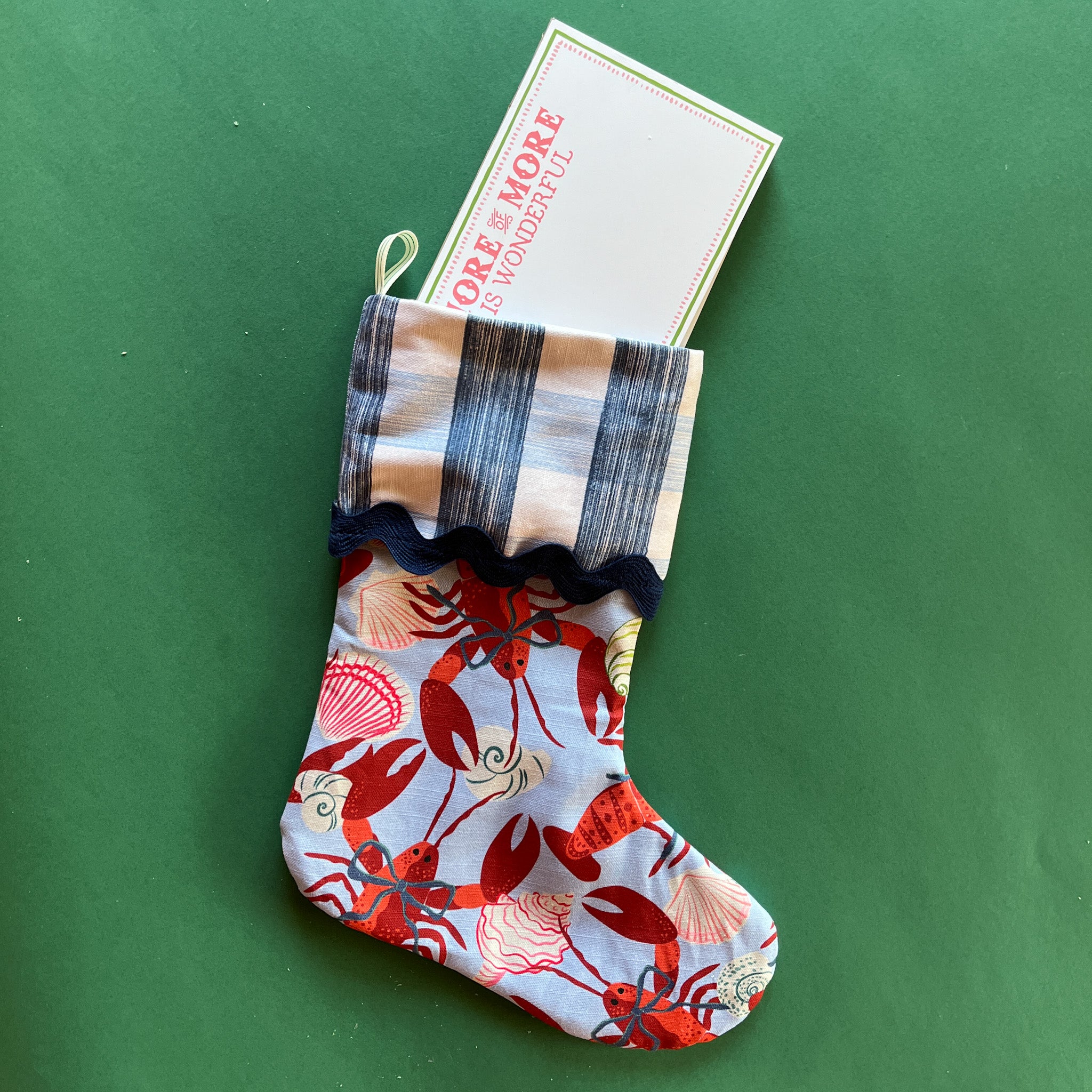 A lobster print red and blue Christmas stocking with a folded gingham top