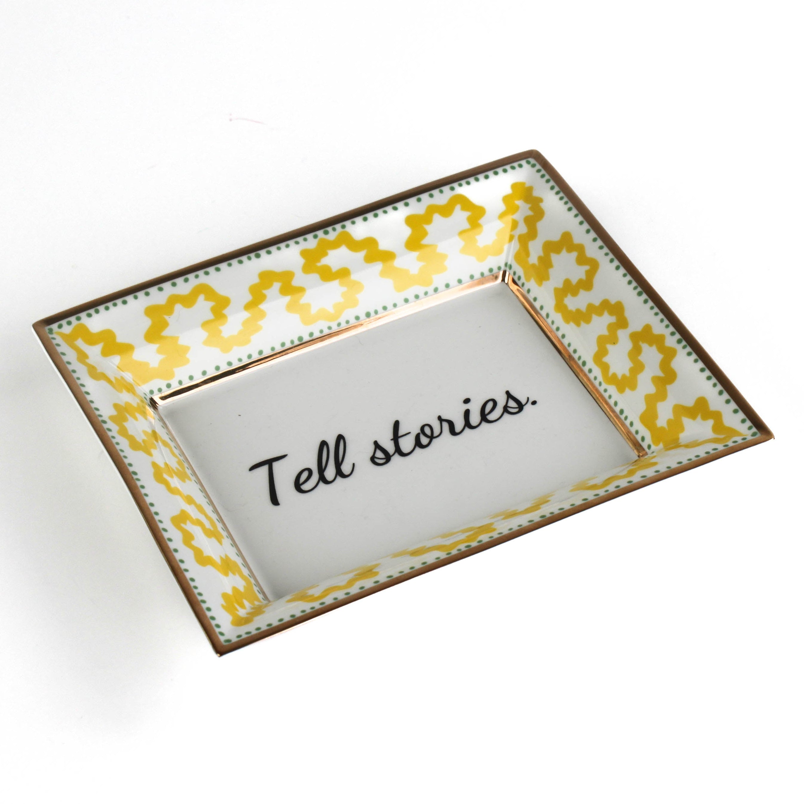 Madcap Cottage yellow and white porcelain trinket tray with a gold border and a saying that says Tell Stories.