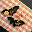 Madcap cottage black bat shaped halloween plates resting on orange gingham paper table runner