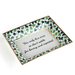 A rectangular porcelain trinket tray with a blue-and-green gingko-leaf patterned trim and gilt edging. The tray has text inside that reads 'You only live once, so don't settle for boring and expected.
