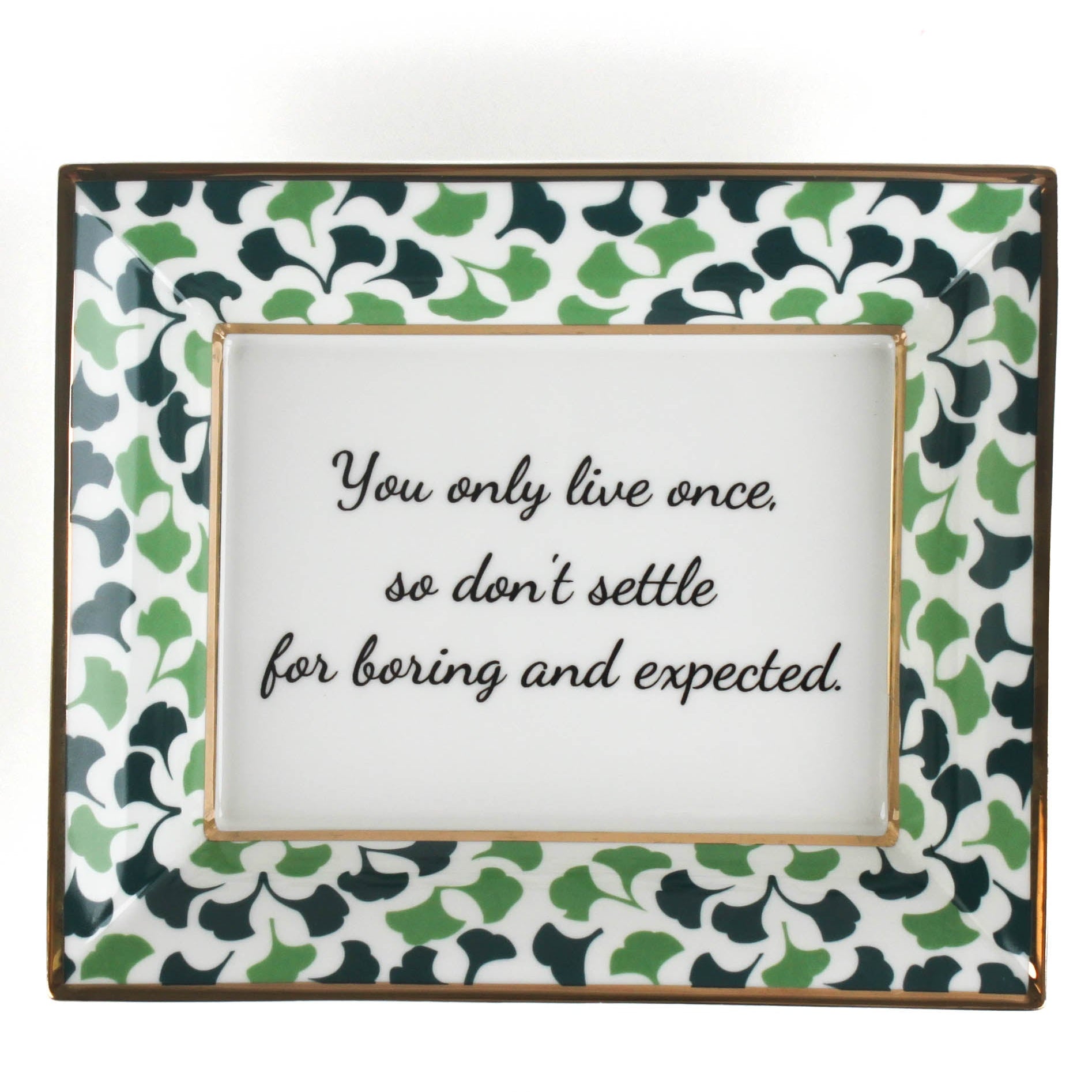 A rectangular porcelain trinket tray with a blue-and-green gingko-leaf patterned trim and gilt edging. The tray has text inside that reads 'You only live once, so don't settle for boring and expected.