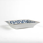 side view of the Madcap Cottage blue and white trinket tray with a gold border and a saying that says The less you talk, the smarter you seem. 