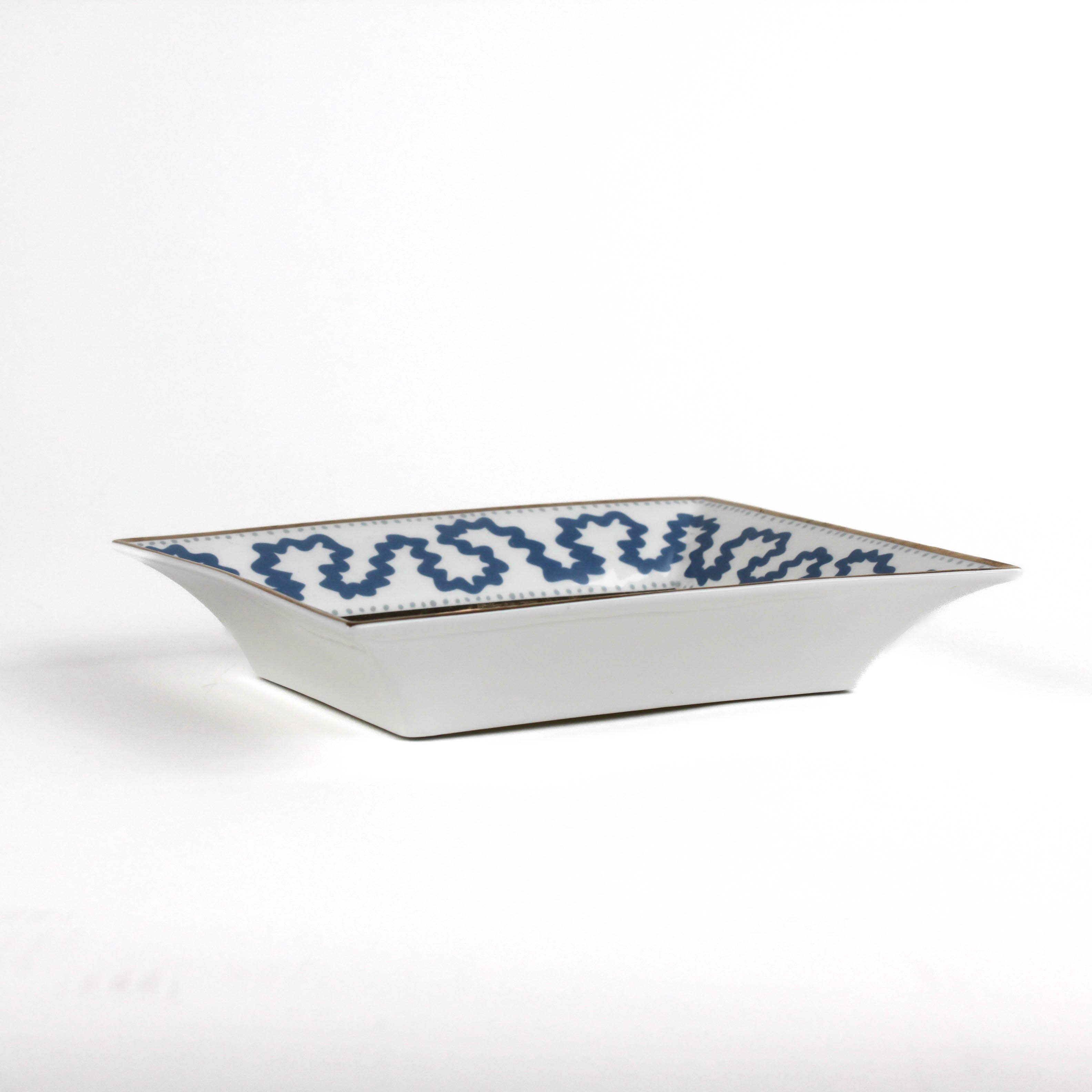 side view of the Madcap Cottage blue and white trinket tray with a gold border and a saying that says The less you talk, the smarter you seem. 