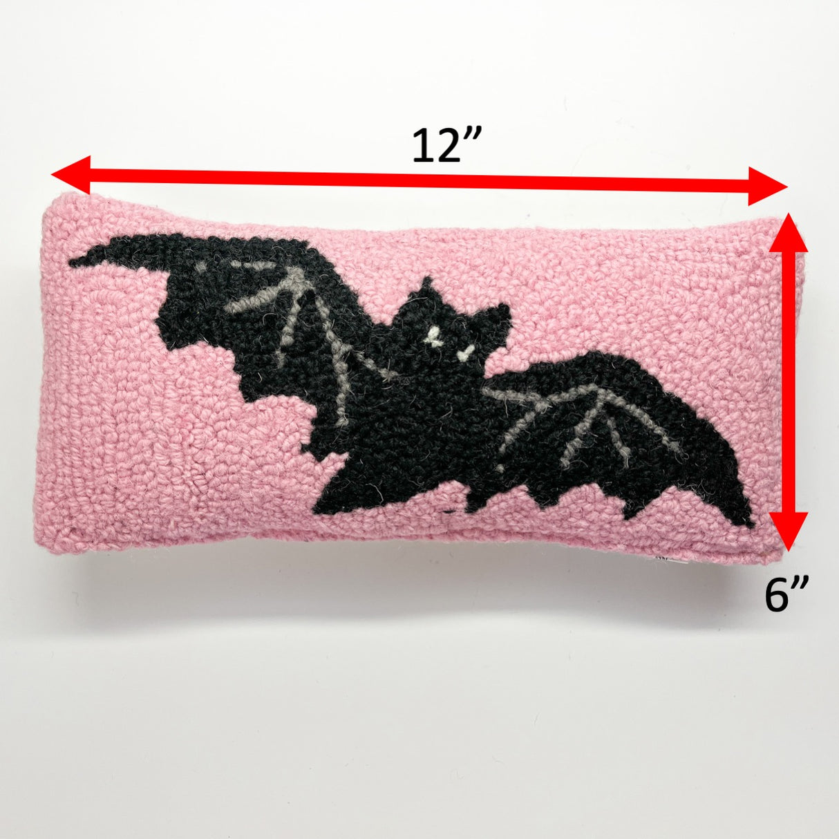 A pink wool lumbar Halloween accent throw pillow with black bat design with a size/dimension of 12" by 6"