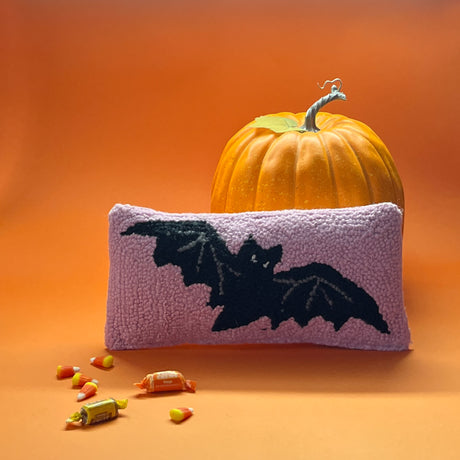 A pink wool lumbar halloween accent pillow with black bat design