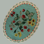 A blue oval rug with strawberry and flower motifs and a scalloped border
