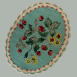 A blue oval rug with strawberry and flower motifs and a scalloped border