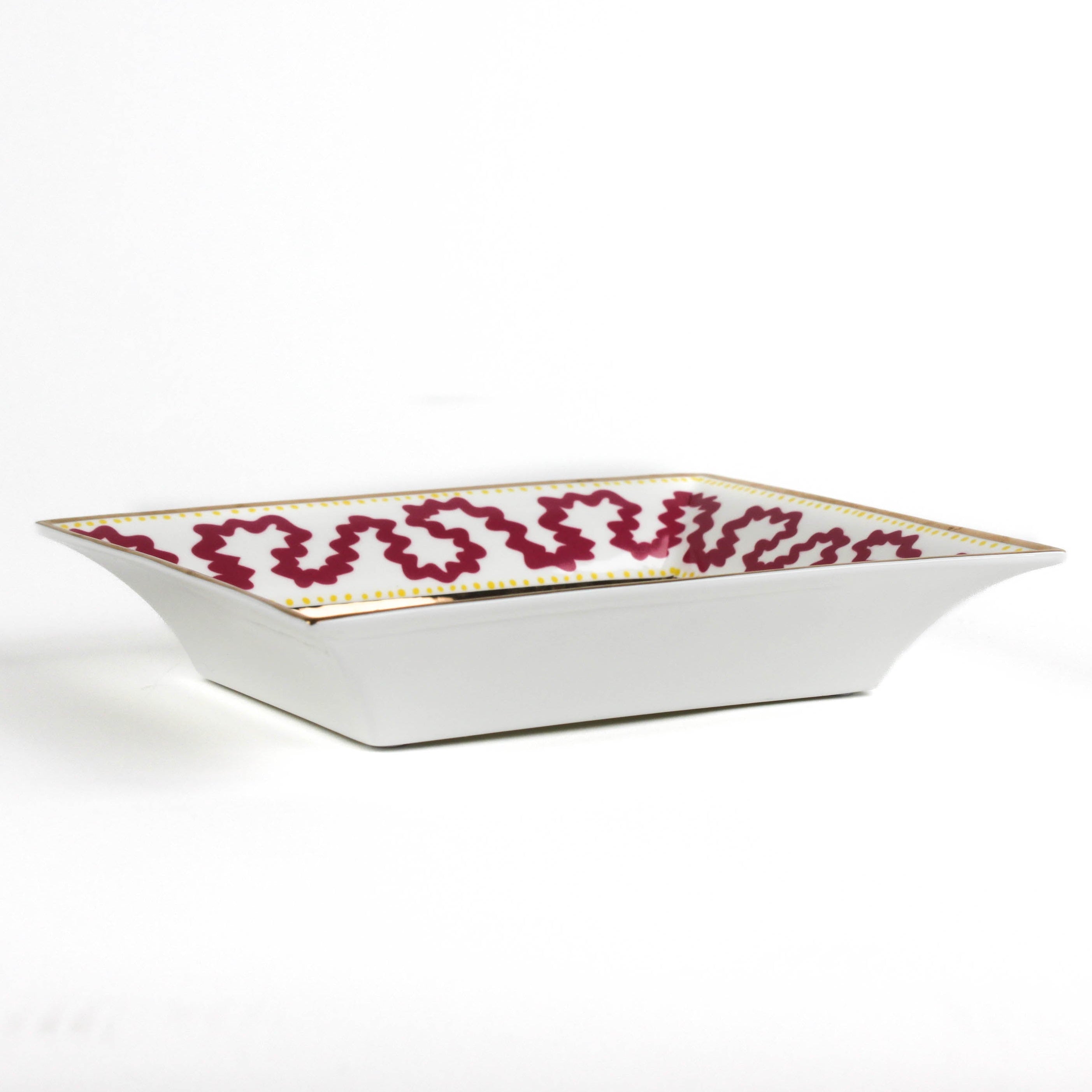 side view of the Madcap cottage pink and white porcelain trinket tray with a gold border and a saying that says If you want to be neutral move to Switzerland.