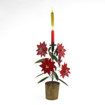 A large tole metal christmas candle holder in the shape of a poinsettia plant.