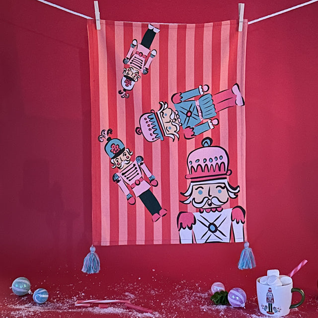 Four Nutcrackers on Pink and Red Stripe Background Tea Towel
