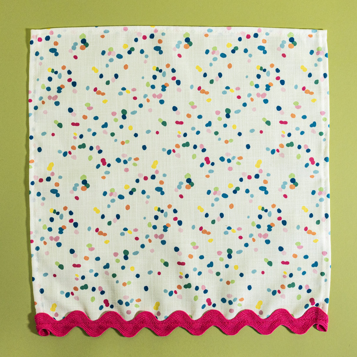 A confetti print fabric napkin from Madcap Cottage on a light green background.
